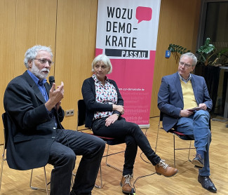 Christoph Bals, Christiane Bals und Dekan Jochen Wilde sitzend. Im Hintergrund ein Rollup mit dem Schriftzug "Wozu Demokratie".